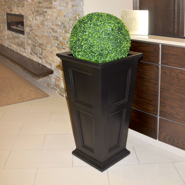 An espresso Mayne Fairfield planter with a green bush in it.