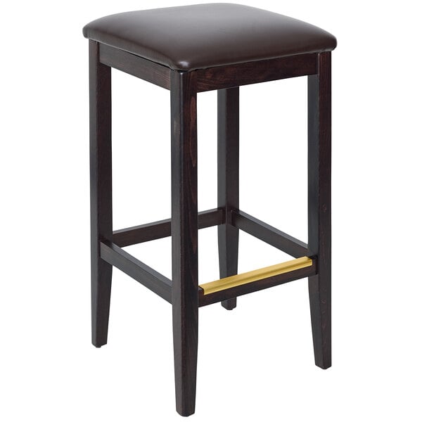 A BFM Seating dark walnut beechwood barstool with dark brown cushion on a table in a bar.