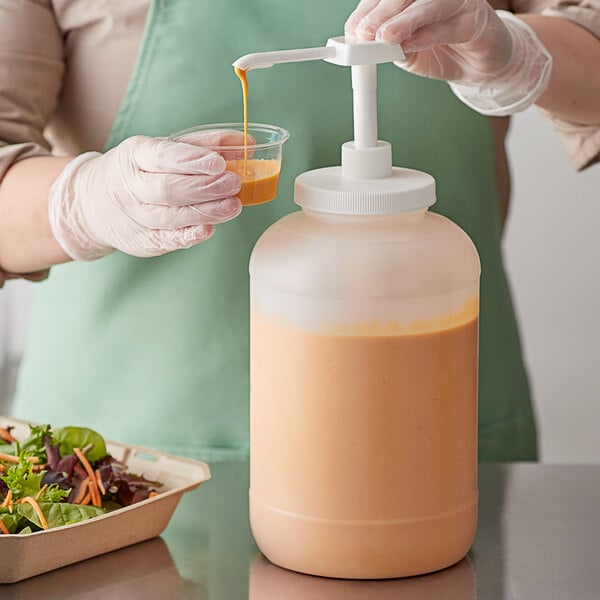 A gloved person using a Choice condiment pump to pour liquid into a white container.