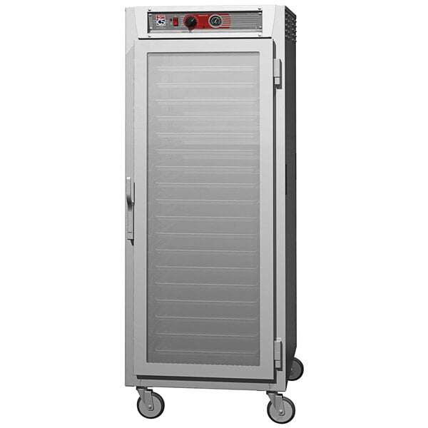 A Metro C5 holding cabinet with a clear glass door and wheels.