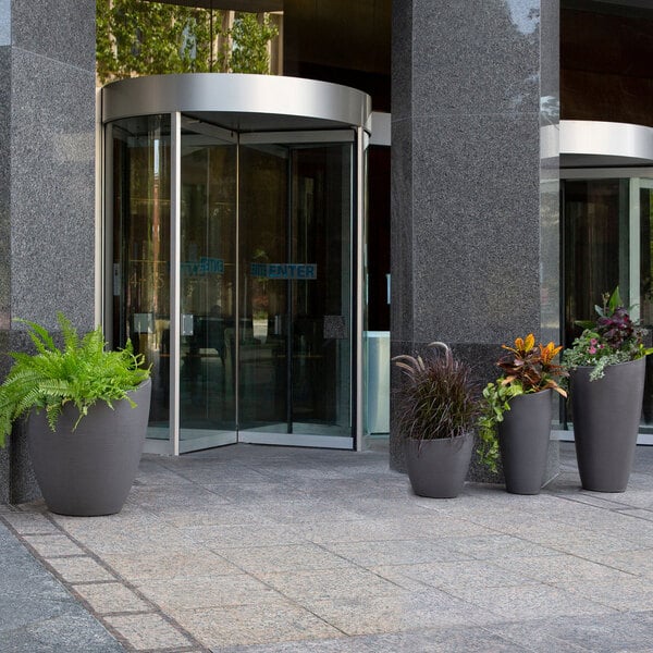 A group of four Mayne Modesto graphite grey planters with plants in them.