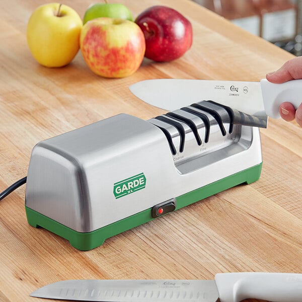Electric knife sharpener on a wooden counter next to apples