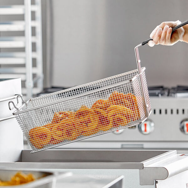 A person using an Anets fryer basket to fry food.