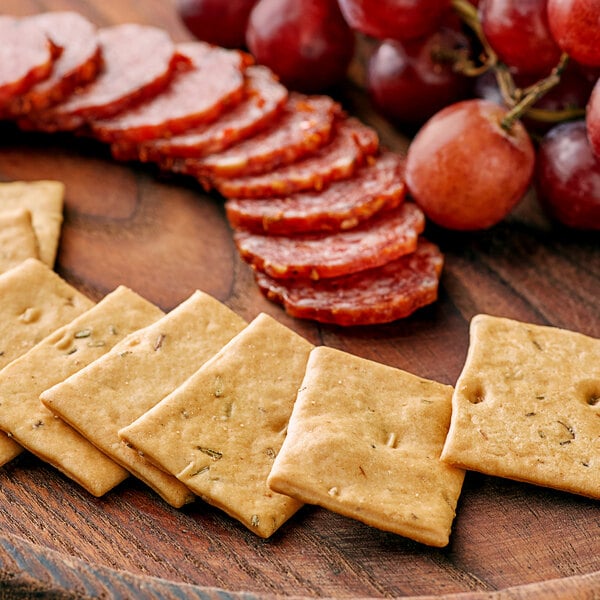 A plate of Meliora Baked Rosemary Focaccia Bites on a wooden surface with grapes.