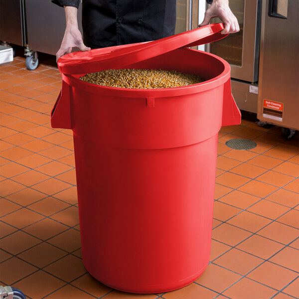 A man holding a red round ingredient storage bin full of grains.