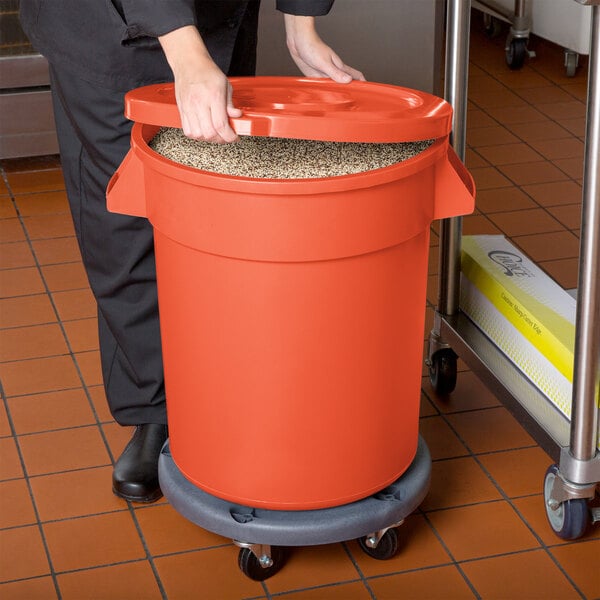 A person holding a large orange bucket with a lid.