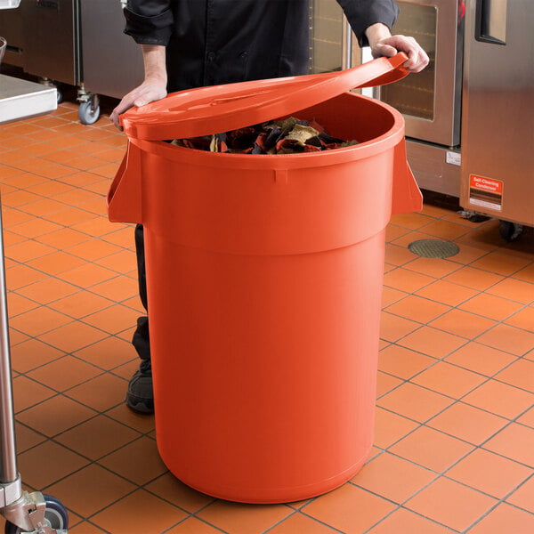 A woman holding a large orange round ingredient storage bin with a lid.