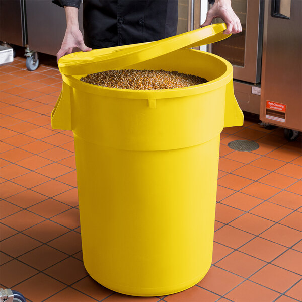 A man holding a yellow round ingredient storage bin full of grains.