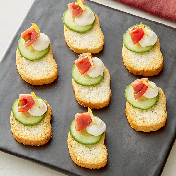 A piece of Meliora Garlic Herb Bruschette Toast with cucumber and cream cheese on top.