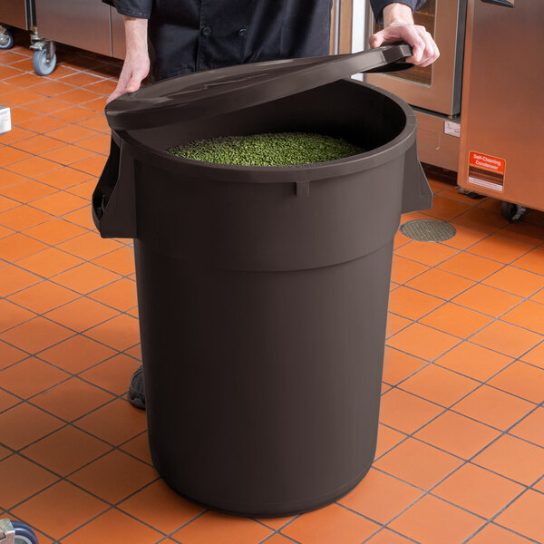 A woman holding a large brown round ingredient storage bin with green beans inside.