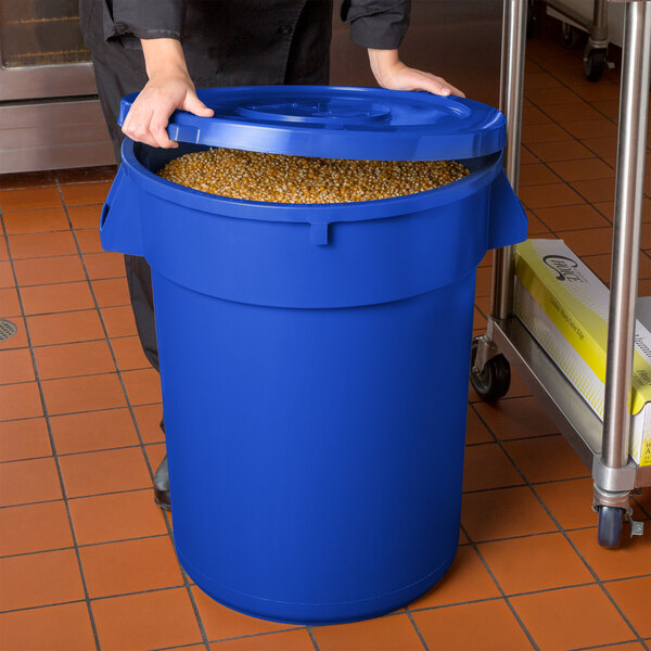 A woman holding a blue plastic container with a lid full of corn.