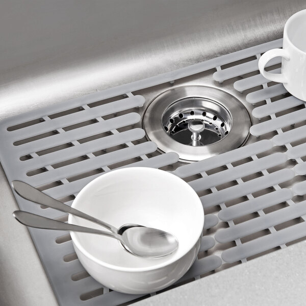 An OXO silicone sink mat in a sink with a bowl and spoon.