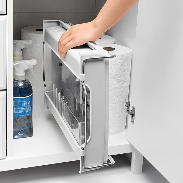 A hand using an OXO Good Grips plastic dish rack on a kitchen counter.
