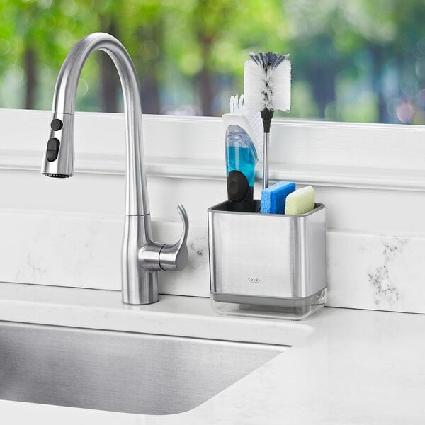 An OXO stainless steel sink caddy on a sink counter.