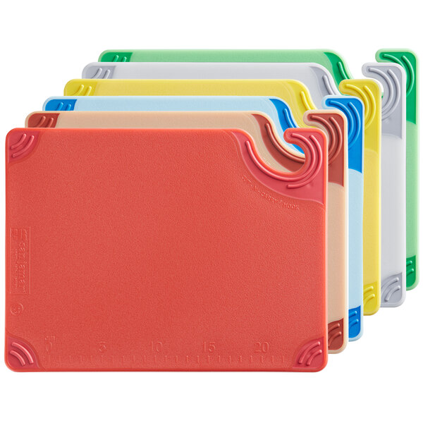 A group of yellow, blue, and white San Jamar Saf-T-Grip plastic cutting boards.