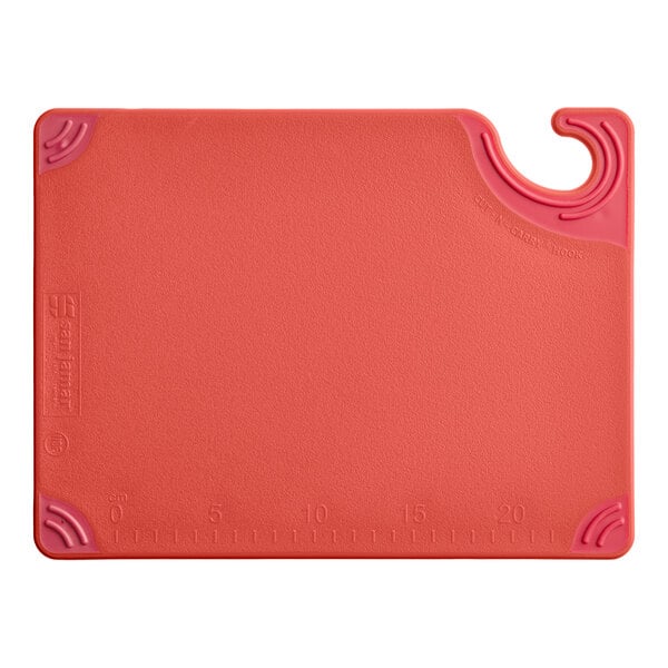 A red rectangular cutting board with a hook and measurement markings along one edge.