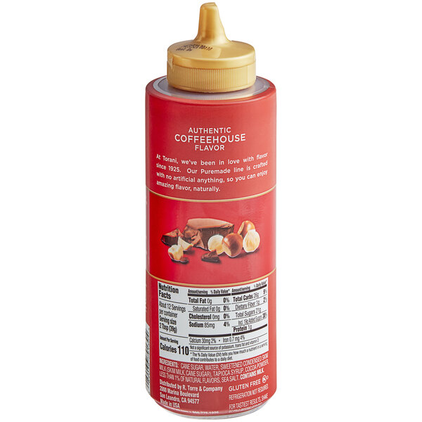 A red bottle of Torani Puremade Chocolate Hazelnut Flavoring Sauce with a yellow cap and white label with pictures of chocolate and nuts.