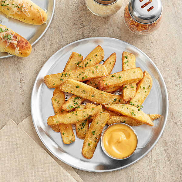 A plate of french fries with dipping sauce on a Choice aluminum pizza pan.