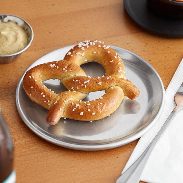 A close-up of a Choice aluminum coupe pizza pan with a pretzel on it.