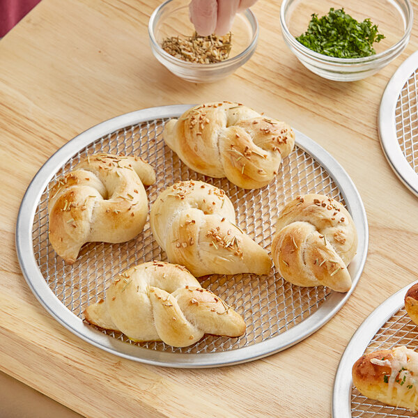 A person using a Choice 9" aluminum pizza screen to bake bread.