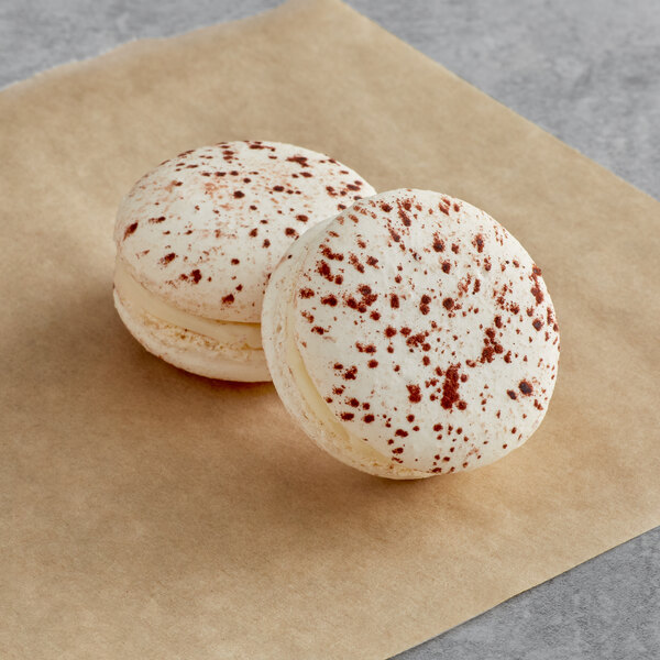 Two Macaron Centrale white chocolate macarons on brown paper.