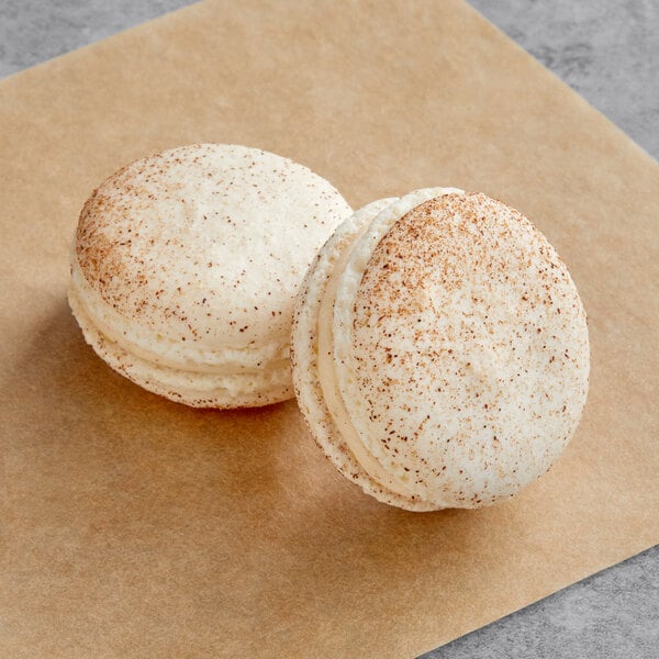 Two Cinnamon Macarons on a brown paper.