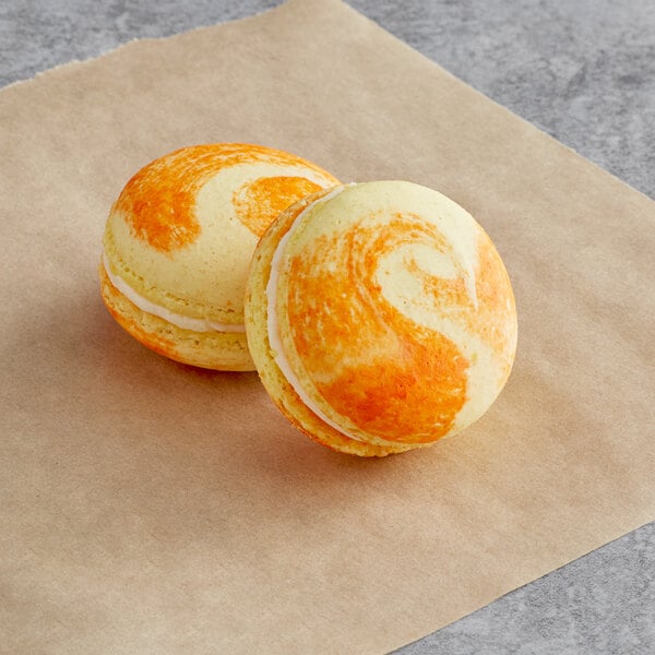 Two Peaches and Cream Macarons from Macaron Centrale on a piece of paper on a table.