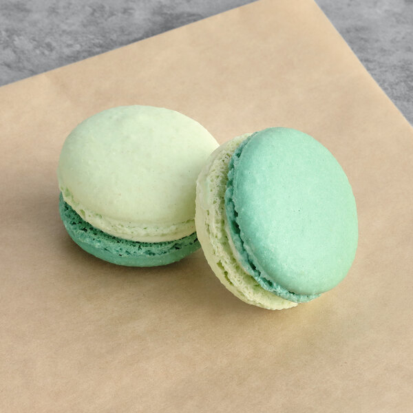 Two Macaron Centrale honeydew macarons on a brown paper.