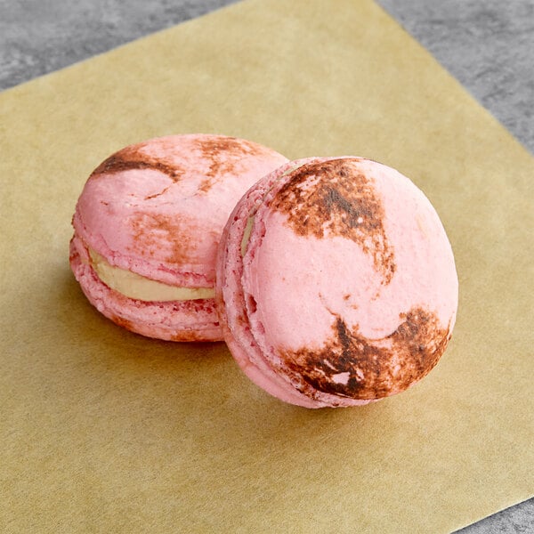 Two pink Macaron Centrale macarons with chocolate on top.