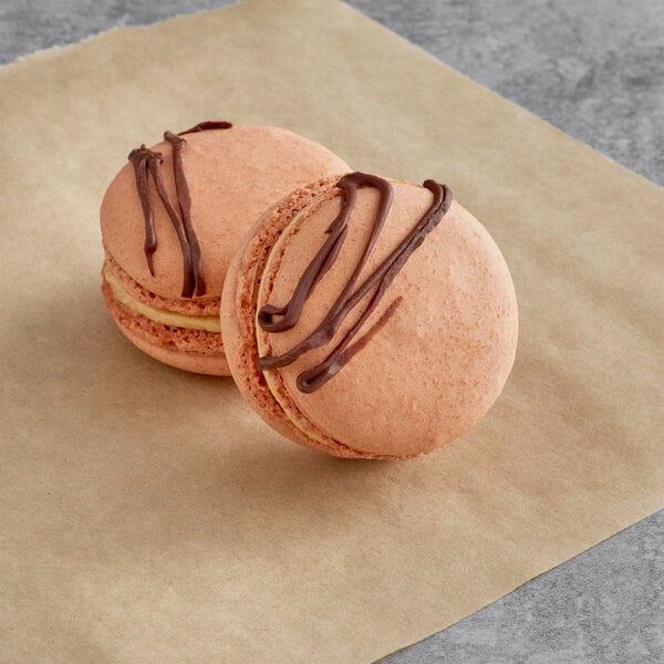 Two chocolate peanut butter macarons on a paper.