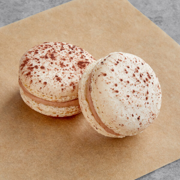 Two Macaron Centrale Tiramisu macarons on a brown paper.