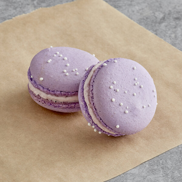 Two purple Macaron Centrale taro macarons on a brown surface.