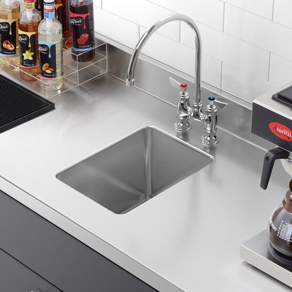 A Regency stainless steel fabricated undermount sink bowl in a counter with a coffee maker.