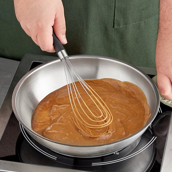 An OXO Good Grips flat whisk stirring brown liquid in a bowl.