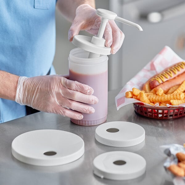 A person in gloves using a Choice condiment pump to fill a container with pink liquid.