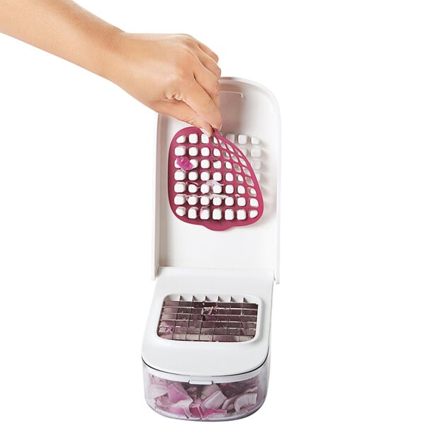 A person using an OXO vegetable chopper with a red and white lid.