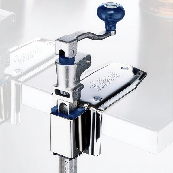 An Edlund Old Reliable #1 manual can opener with a stainless steel base on a table.