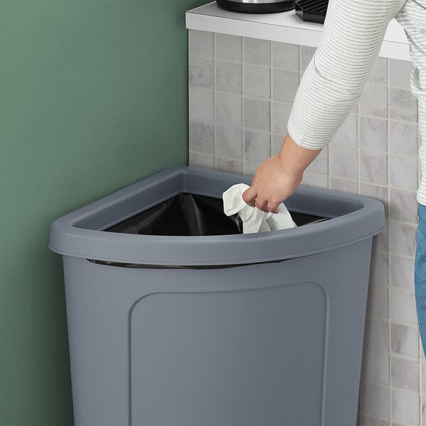 A hand using a white towel to clean a Lavex corner round trash can lid.