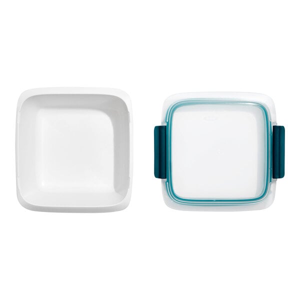 A square white container with a matching snap-on lid featuring blue side clasps, shown from above with the lid removed and placed next to the container.