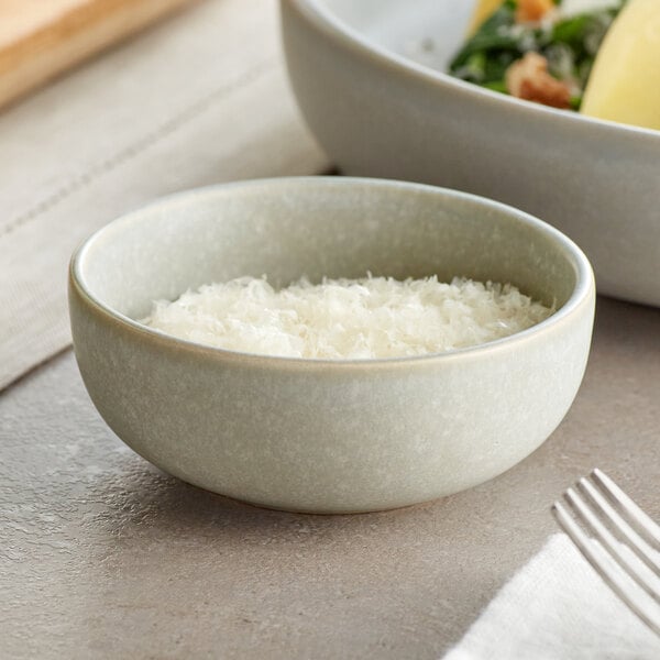 An Acopa Pangea ramekin filled with food on a table next to a plate of food.