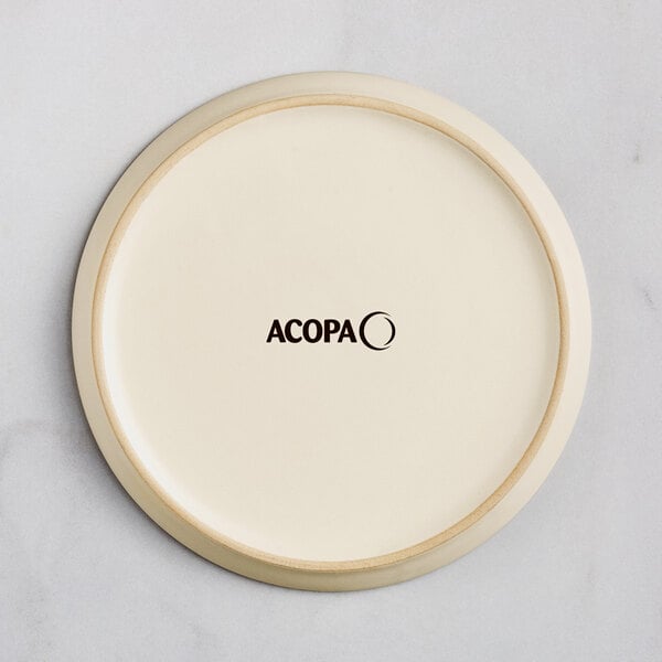 An Acopa Pangea white matte porcelain coupe plate with the word Acopa in black.