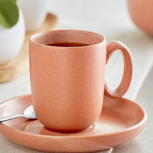 A white Acopa Terra Cotta cup on a saucer with tea in it.
