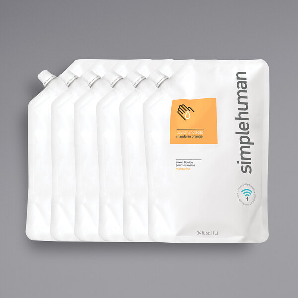 A group of white plastic bags with orange labels for simplehuman Mandarin Orange Scented Liquid Hand Soap refill pouches.