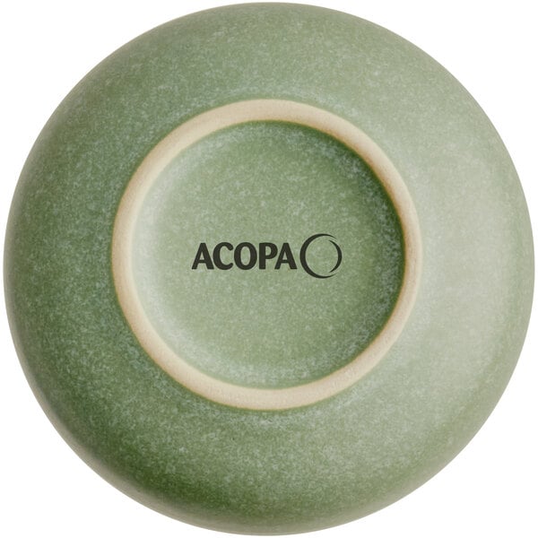A sage green Acopa porcelain ramekin with a black circle and text.