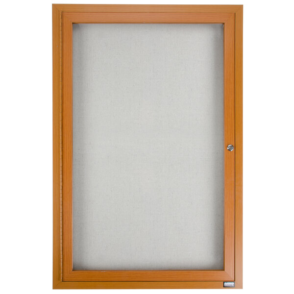 An oak wooden framed enclosed bulletin board with a light.