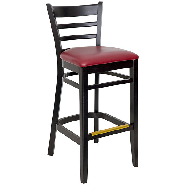 A black BFM Seating Berkeley ladder back barstool with a burgundy vinyl seat.