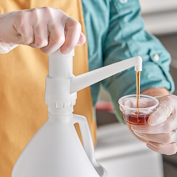 A person using a Choice plastic condiment pump to pour liquid.