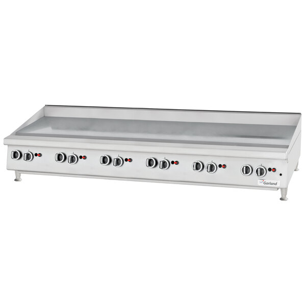 A white countertop with a Garland chrome griddle and knobs.