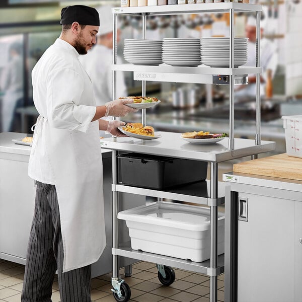 A chef in a white coat preparing food on a Regency expeditor table.