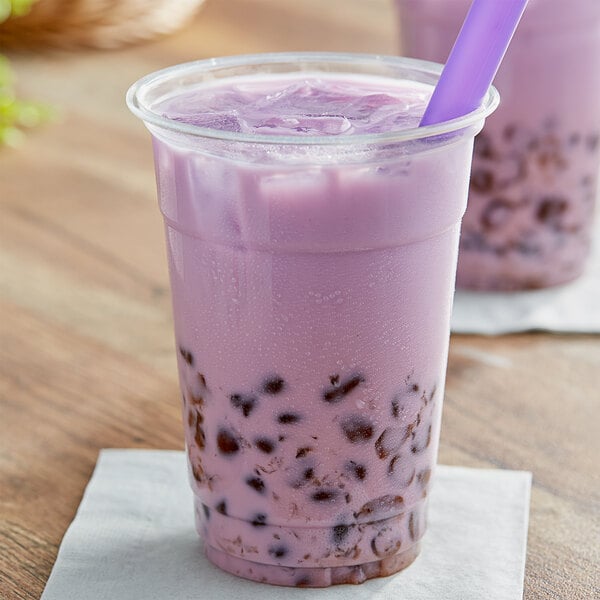 A cup of bubble tea with purple liquid and brown Fanale boba with a purple straw.